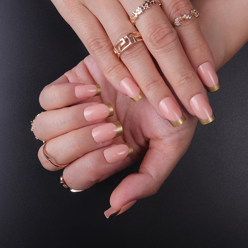 Nude press-on nails with gold half-moon tips and glossy finish